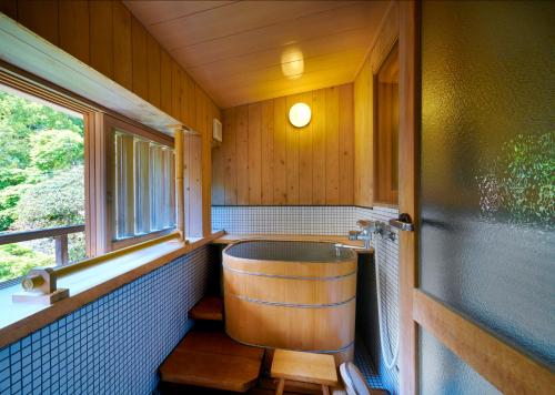 a bathroom with a tub in a room with a window at AKARI et KAORI formerly Taizanso in Izu