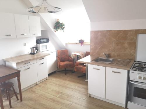 a kitchen with white cabinets and a sink and a table at Apartament 2pokojowy 4-5osobowy in Węgorzewo