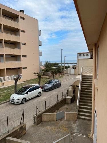 2 voitures garées dans un parking à côté d'un bâtiment dans l'établissement magnifique appartement en bord de mer, à Valras-Plage