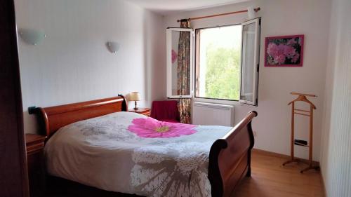 Un dormitorio con una cama con una flor rosa. en Chambre à louer chez l'habitant en Payré