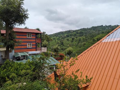 a house with an orange roof next to a mountain at The Door to Nirvana Backpackers Hostel Kotagiri in Kotagiri