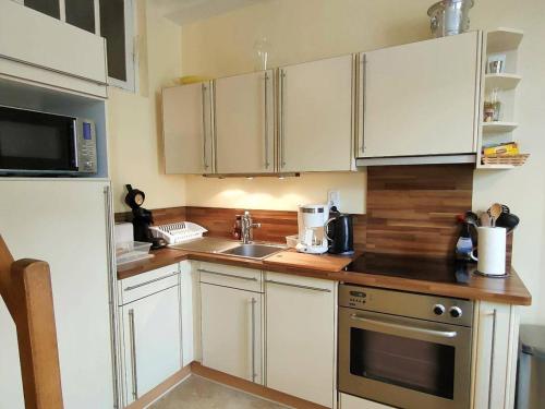 une cuisine avec des armoires blanches, un évier et un réfrigérateur dans l'établissement Appartement Duplex pour 4/5 pers. Proche Centre, Parking Gratuit, Cauterets - FR-1-234-179, à Cauterets