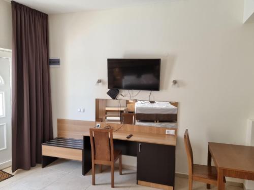 a room with a desk and a bed with a television at Бутикови Студиа БРИТА in Kranevo