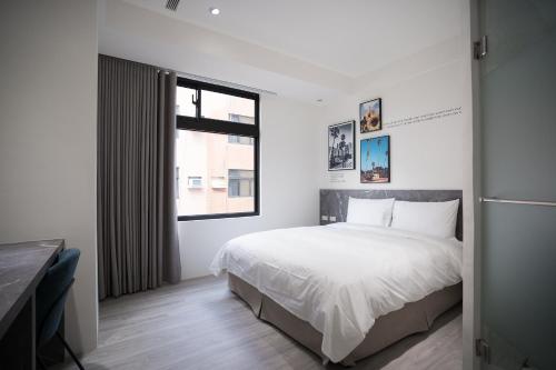 a bedroom with a white bed and a window at The Way Inn in Taichung