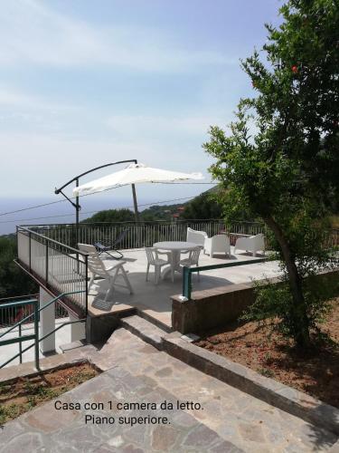 a patio with a table and chairs and an umbrella at Fascino del Cilento in Caprioli
