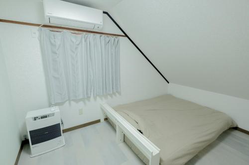 a small white room with a bed and a window at Lake Toya and Nakajima in Lake Toya