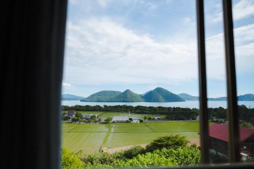 a view from a window of the water and mountains at Lake Toya and Nakajima in Lake Toya