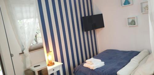 a small bedroom with a blue and white striped wall at Dom Przy Plaży in Sarbinowo