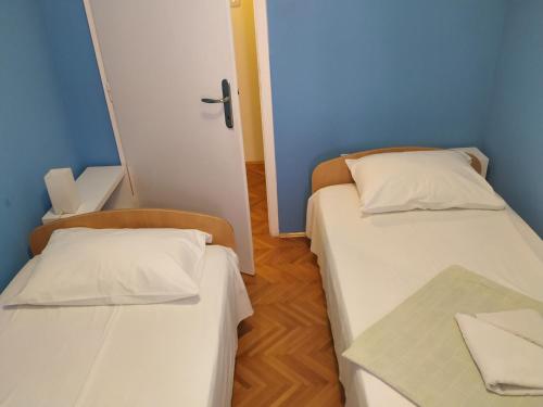 two beds in a room with blue walls and wooden floors at Apartmani Abeona in Budva