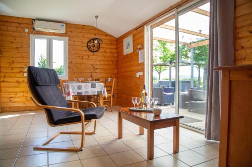 un salon avec une chaise et une table dans l'établissement Chalet Mélèze - Les Chalets de Barruérot - Spa jacuzzi privatif - Piscine en été, à Peyrusse-Grande