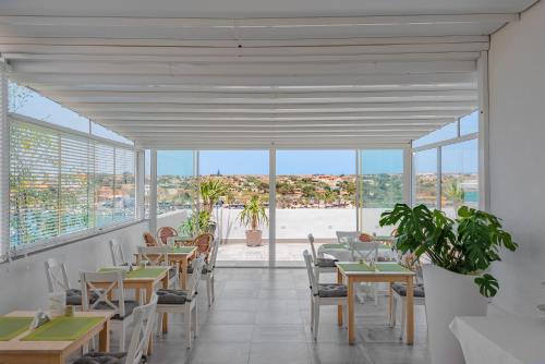 a dining room with tables and chairs and windows at Hotel Vega in Lampedusa