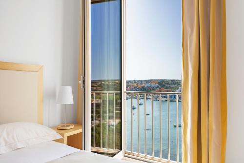 a bedroom with a large window with a view of the water at Hotel Vega in Lampedusa