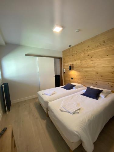 two beds in a large room with a wooden wall at Hotel Le Chalet in Sainte-Marie-de-Campan