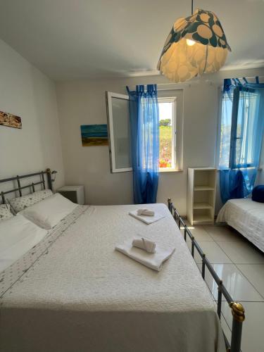 a bedroom with two beds and a window with blue curtains at Casette Santini B&B in Casalbordino