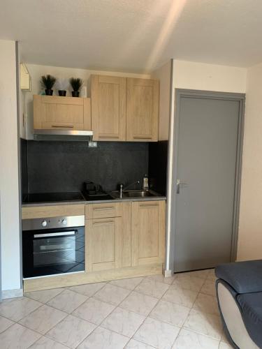 une cuisine avec des armoires en bois, un évier et une cuisinière dans l'établissement Bel Appartement en bord de mer, accès direct à la plage, au Barcarès
