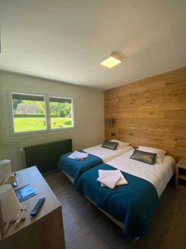 a bedroom with two beds and a desk and two windows at Hotel Le Chalet in Sainte-Marie-de-Campan