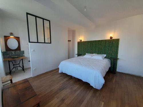 - une chambre avec un grand lit et une tête de lit verte dans l'établissement Maravillon - Chambres d'hôtes, à Villon