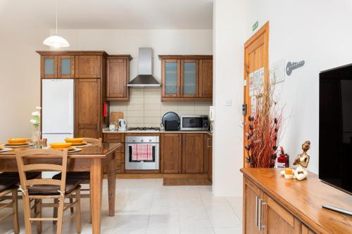 a kitchen with wooden cabinets and a table with chairs at Spacious, Bright & Cosy 2 Bedroom 2 Bathroom Apartment - Msida Uni Heights in Msida