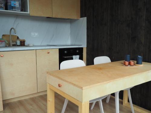 a kitchen with a wooden table and white chairs at Steigen Lodge Tiny house in Steigen