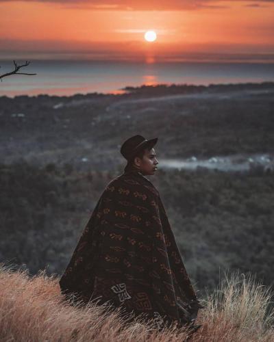 a man standing in a field with the sunset in the background at Sumberkima Hill 2 in Pemuteran