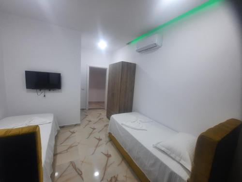a bedroom with two beds and a tv on the wall at HOTEL MEGNIAR in Lushnjë