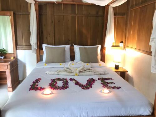 a bed with a heart made out of flowers and candles at Friendly Homestay Lemukih in Singaraja