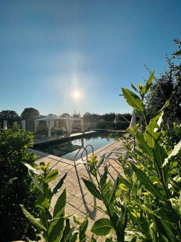 a view of a pool with the sun in the background at Masseria Montanaro in Cisternino