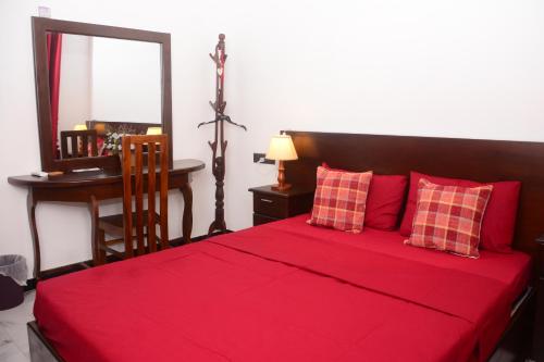 1 dormitorio con cama roja con espejo y escritorio en Concey Transit Hotel Airport view, en Katunayake