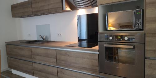 a kitchen with a stove and a microwave at MAISON DANS LE CHARMANT VILLAGE DE LA VRAIE-CROIX in La Vraie-Croix