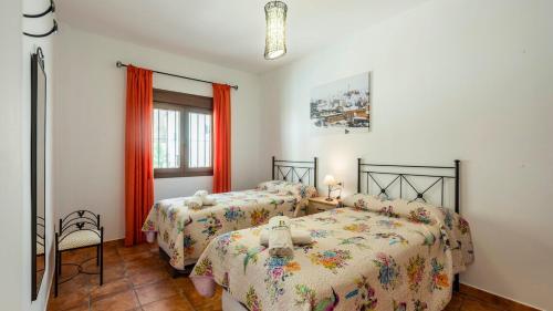 two beds in a bedroom with orange curtains at Casa Rural Sierra de las Nieves Yunquera by Ruralidays in Yunquera