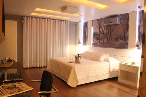a bedroom with a bed and a table and a desk at Hotel Areias Brancas in Rosário do Sul