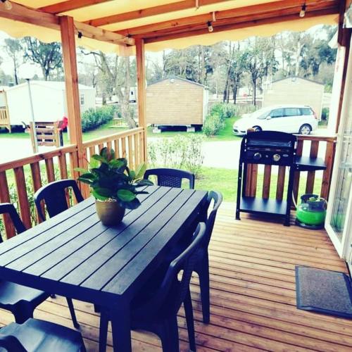 une table et des chaises en bois sur une terrasse en bois dans l'établissement Mobilhome climatisé 6 psn, à Lège-Cap-Ferret