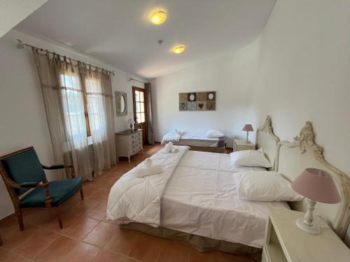 ein Schlafzimmer mit einem großen weißen Bett und einem Stuhl in der Unterkunft Le Mas de la Vinçane in Pernes-les-Fontaines