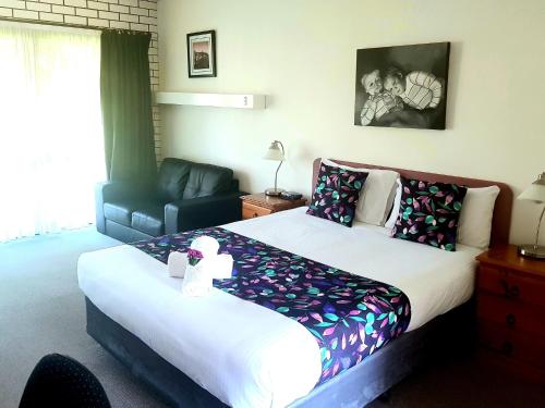 een slaapkamer met een groot bed en een bank bij Barooga Country Inn Motel in Barooga