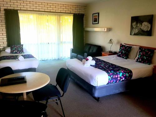 Habitación de hotel con 2 camas y mesa en Barooga Country Inn Motel, en Barooga