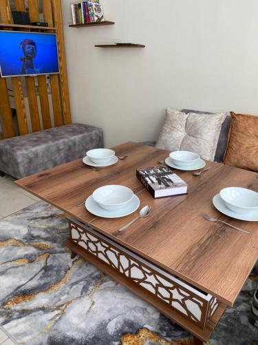 a wooden table in a living room with plates on it at Olivia Apartment at Ölüdeniz - Central in Oludeniz