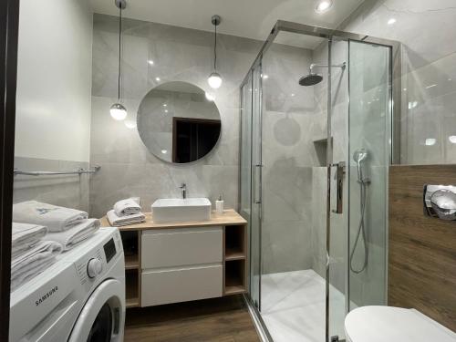 a bathroom with a shower and a washing machine at 3L Apartments Aquarius in Kołobrzeg