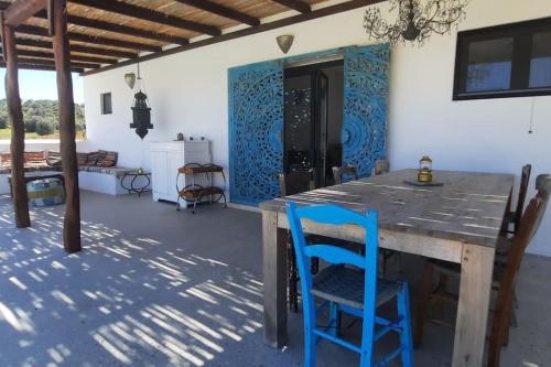 uma sala de jantar com uma mesa de madeira e cadeiras azuis em Villa Louloudia stylish luxury villa with private pool em Pitsidia