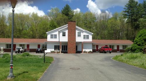 a white house with a brick chimney on a street at Economy Lodge 682 Main St Sturbridge in Sturbridge