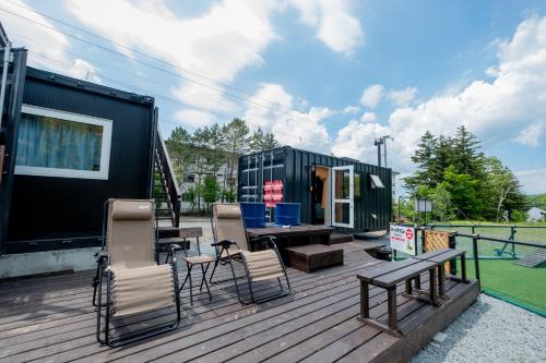 美瑛町にあるPet-friendly C Hotel Biei Shiroganeのデッキに椅子とテーブルが置かれた緑の小さな家