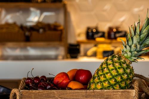 a basket of fruit with a pineapple and apples at Manifest Boutique Hotel in Oítilon
