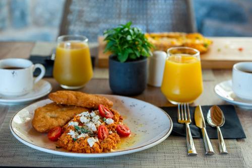 a table with a plate of food and orange juice at Manifest Boutique Hotel in Oítilon