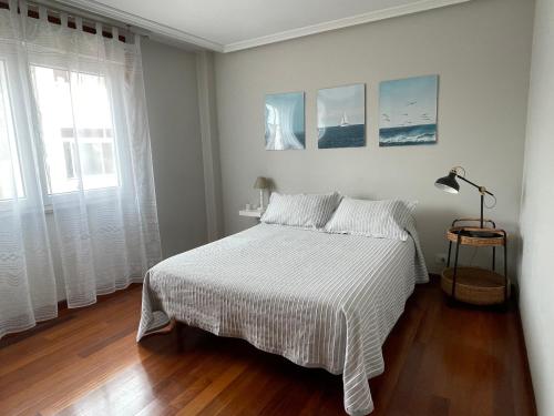 a white bedroom with a bed and a window at Apartamento A Tenencia in Sada