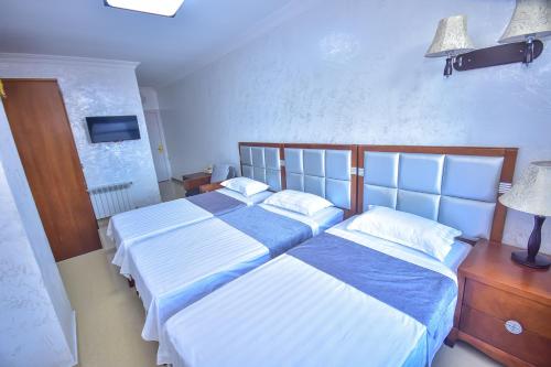a bedroom with two beds and a tv on the wall at Hotel Chveni Sakhli in Batumi