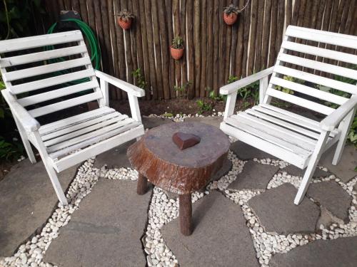 two white chairs and a table with a wooden stump at Pousada Miramar in Marataizes