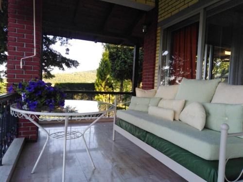 a couch on a porch with a table and flowers at Το σπίτι με τα έλατα 