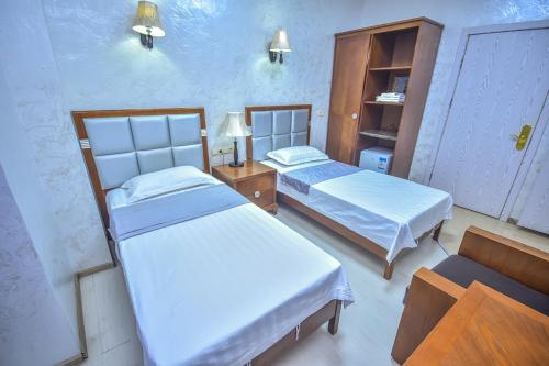 a room with two beds and a cabinet at Hotel Chveni Sakhli in Batumi