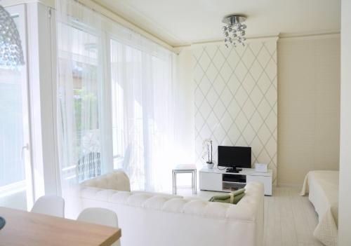 a living room with a white couch and a tv at Cloé Apartman in Szeged