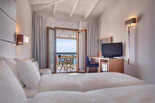 a hotel room with a bed and a television at Valtos Beach Hotel in Parga