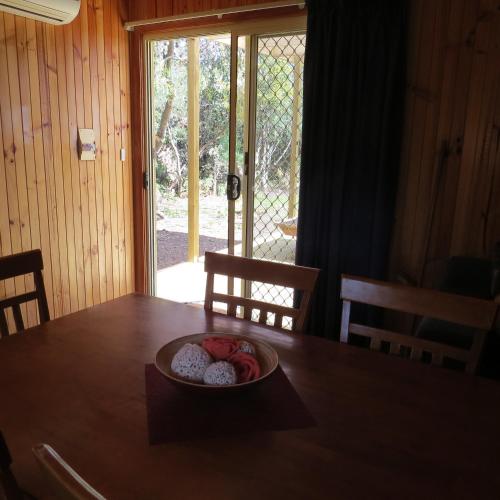 a plate of food on a wooden table with a window at Captain Cook Holiday Park in Adventure Bay